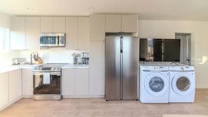Una cucina moderna con elettrodomestici in acciaio inossidabile, tra cui frigorifero, forno e lavatrice.