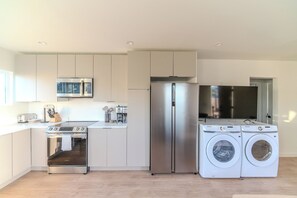 A modern kitchen with stainless steel appliances, including a refrigerator, oven, and washing machine. - Long Beach 3 Bedroom Apartment Near Beach, Dining, CSULB, Long Beach Airport (Long Beach)