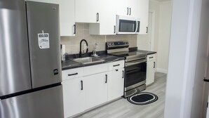 Une cuisine moderne dotée d’appareils électroménagers en acier inoxydable, de meubles blancs et d’un tapis à motifs noir et blanc.