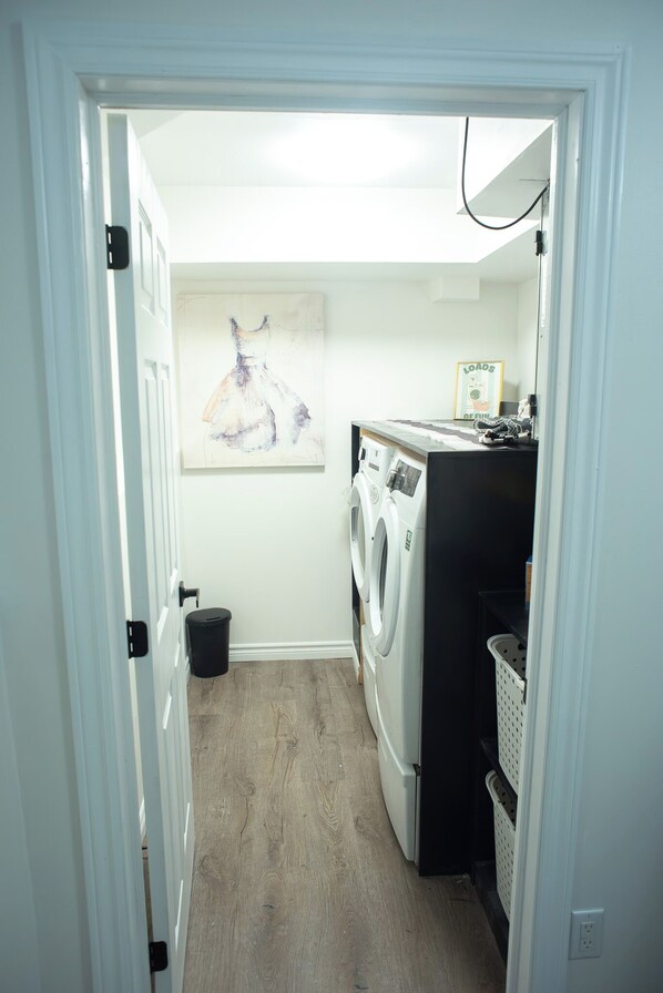 A laundry room with a washing machine, dryer, and a painting on the wall.