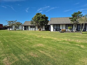 A row of modern buildings with a well-maintained lawn in front. - Magnolia Court Motel (Ōpōtiki)
