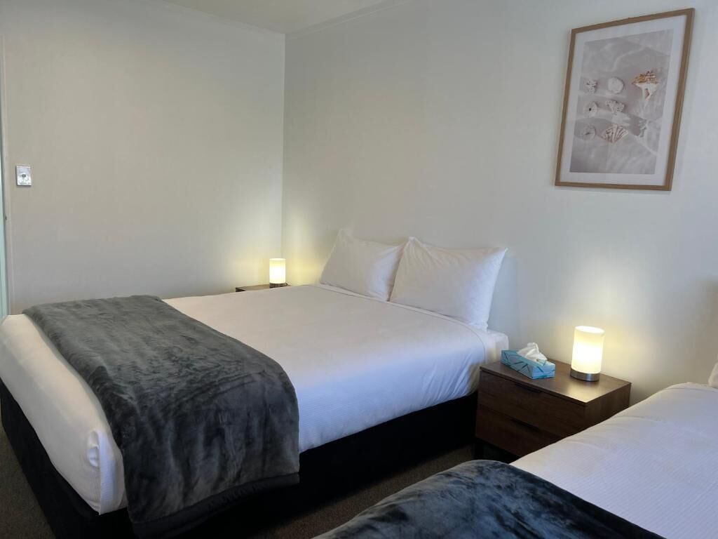 Habitación de hotel con cama, mesitas de noche y un cuadro en la pared.