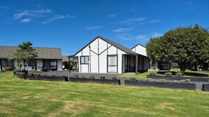 A two-story building with a gabled roof, a covered porch, and a well-maintained lawn. - Magnolia Court Motel (Ōpōtiki)