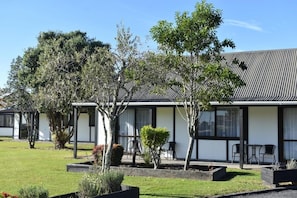 A modern building with a flat roof, large windows, and a well-maintained lawn with various plants. - Magnolia Court Motel (Ōpōtiki)