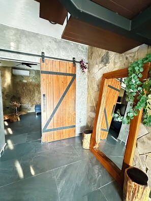 A modern interior with a wooden sliding door, a stone wall, and a plant.