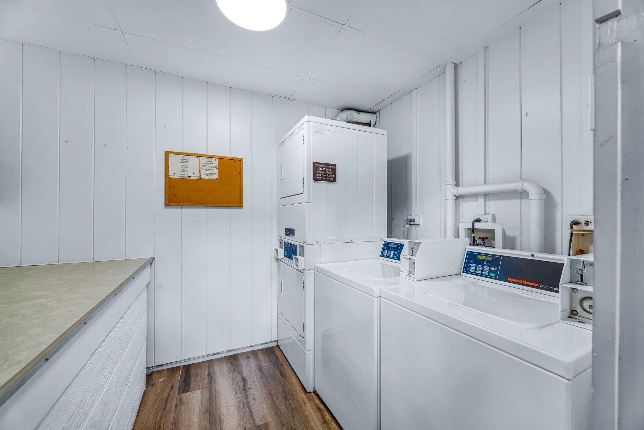 A laundry area with a washing machine, dryer, and a bulletin board.