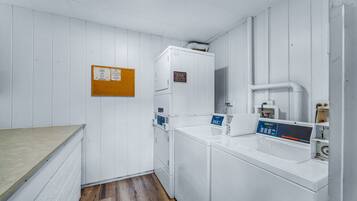 A laundry area with a washing machine, dryer, and a bulletin board.