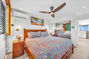 A bedroom with a bed, a ceiling fan, a painting, and a window with a view. - Beachfront at The Pikake, ocean views (Lahaina)