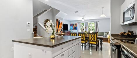 Una cocina moderna con armarios blancos, encimera de granito y electrodomésticos de acero inoxidable.