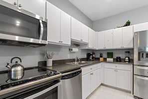 Een moderne keuken met roestvrijstalen apparatuur, witte kastjes en een granieten aanrecht.