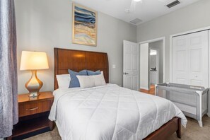 A bedroom with a bed, a nightstand with a lamp, a headboard, a door, and a radiator. - Family-Friendly 3BR Townhouse with Outdoor Patio & Fire Pit 🌴 (Cape Canaveral)