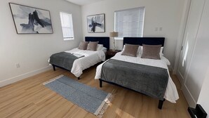 Quarto com duas camas, mesa de cabeceira, abajur e obras de arte nas paredes.