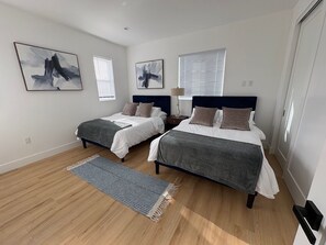 Ein Schlafzimmer mit zwei Betten, einem Nachttisch, einer Lampe und Bildern an den Wänden.