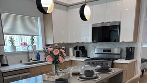 Uma cozinha moderna com ilha central, banquetas e iluminação pendente.