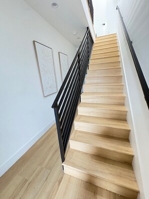 Eine Treppe mit Holzdielen und schwarzen Geländern, die zu einer oberen Etage führt.