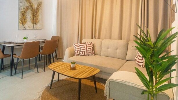 Una sala de estar con un sofá, una mesa de comedor con sillas, un ventilador de techo y una planta en maceta.