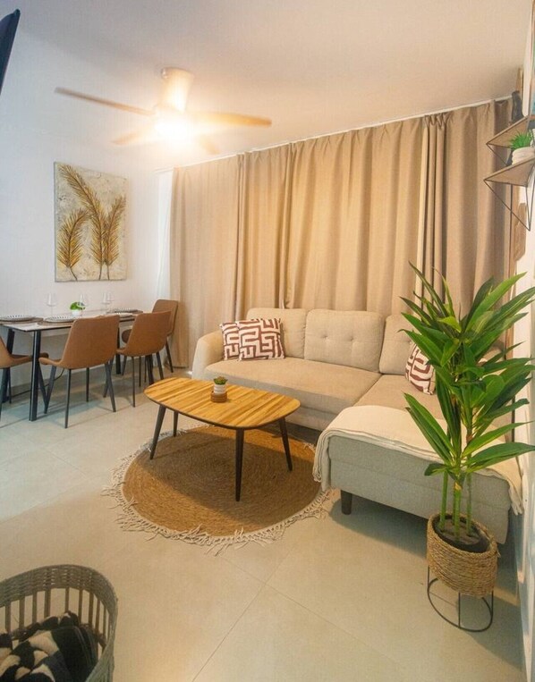 A living room with a sofa, a dining table with chairs, a ceiling fan, and a potted plant. - ANYA 1 Bayahibe Apartment for Couples and friends (Bayahibe)