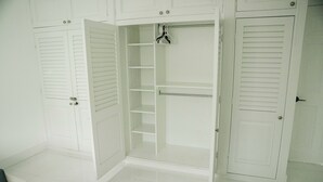 A white closet with sliding doors, shelves, and hanging space. - Skylux Ocean House: 3BR Private Pool, Game Room & Cinema-Size TV (Hollywood)