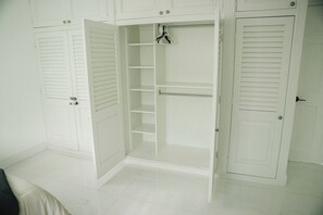 A white closet with sliding doors, shelves, and hanging space. - Skylux Ocean House: 3BR Private Pool, Game Room & Cinema-Size TV (Hollywood)