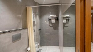A modern bathroom with a glass shower enclosure, a toilet, and a towel rack with folded towels. - RAS VILAS PALACE - Beside Prem Mandir, Vrindavan (Vrindavan)