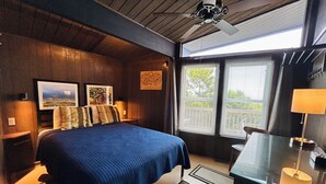 Een slaapkamer met een bed, een bureau, een stoel, een plafondventilator en een raam met jaloezieën.