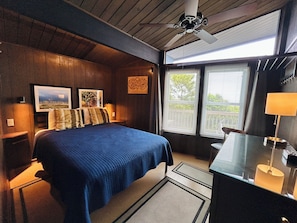 A bedroom with a bed, a desk, a chair, a ceiling fan, and a window with blinds. - Oceanview 3BR, 2BA Holden Beach retreat with WiFi and full kitchen (Holden Beach)