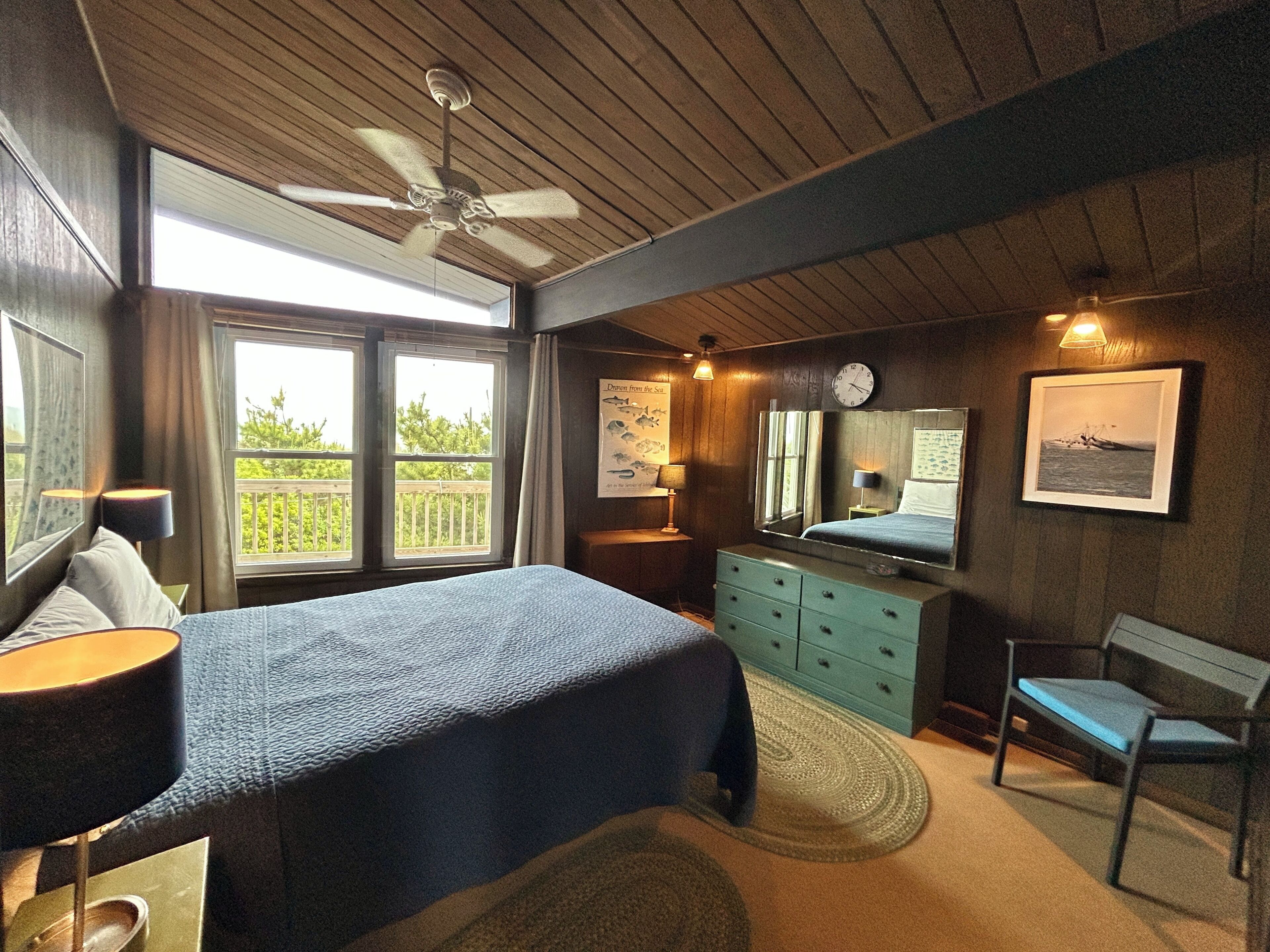 A bedroom with a bed, dresser, chair, and a ceiling fan.