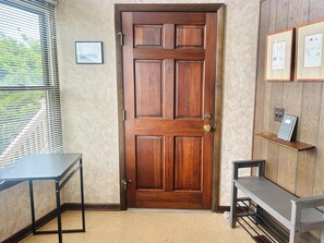 A wooden door with a brass handle, a small table, a bench, and a shelf with framed artwork. - Oceanview 3BR, 2BA Holden Beach retreat with WiFi and full kitchen (Holden Beach)