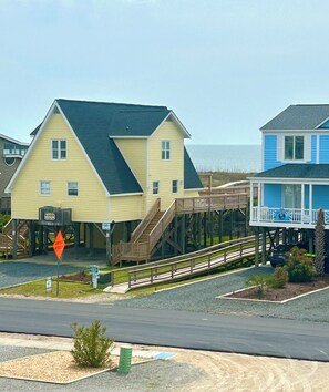 A two-story yellow house with a wooden deck and a staircase leading to a covered area. - 4BR Holden Beach cottage (Holden Beach)