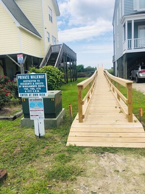 Ein Holzsteg führt zu einem Gebäude, an dem ein Schild mit der Aufschrift 'Private Walkway' den Zugang einschränkt.
