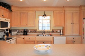 A kitchen with wooden cabinets, a microwave, a coffee maker, and a sink. - 4BR Holden Beach cottage (Holden Beach)