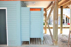Een houten terras met een blauwe deur en een raam.