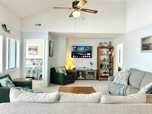 Ein Wohnzimmer mit Sofa, Couchtisch, Fernseher und Bücherregal.