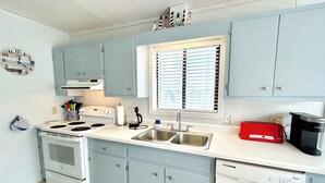 Una cocina con armarios azul claro, una estufa blanca, un fregadero y un tostador rojo.