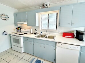 A kitchen with light blue cabinets, a white stove, a sink, and a red toaster. - 3BR Holden Beach retreat with private pool (Holden Beach)