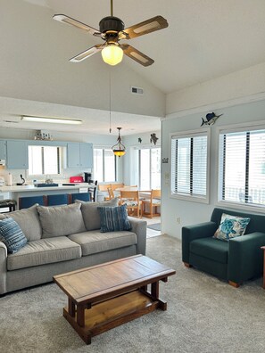 A spacious living area with a ceiling fan, a wooden coffee table, two sofas, and a kitchen in the background. - 3BR Holden Beach retreat with private pool (Holden Beach)