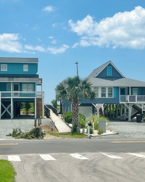 Une propriété située en bord de mer, comprenant un bâtiment à deux étages, une véranda et un escalier menant à l’étage supérieur.