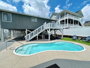 Um imóvel residencial com piscina, um deck coberto e uma casa de dois andares.