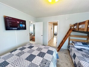 Ein Schlafzimmer mit einem Bett, einem an der Wand montierten Fernseher und einem Stockbett.
