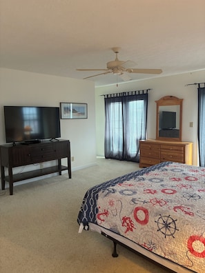 A bedroom with a bed, a dresser, a television, a ceiling fan, and a window with curtains. - 4BR, 4.5BA  Holden Beach home (Holden Beach)