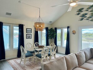 A dining area with a table, chairs, and a hanging light fixture. - 4BR retreat with dock overlooking the ICW (Holden Beach)
