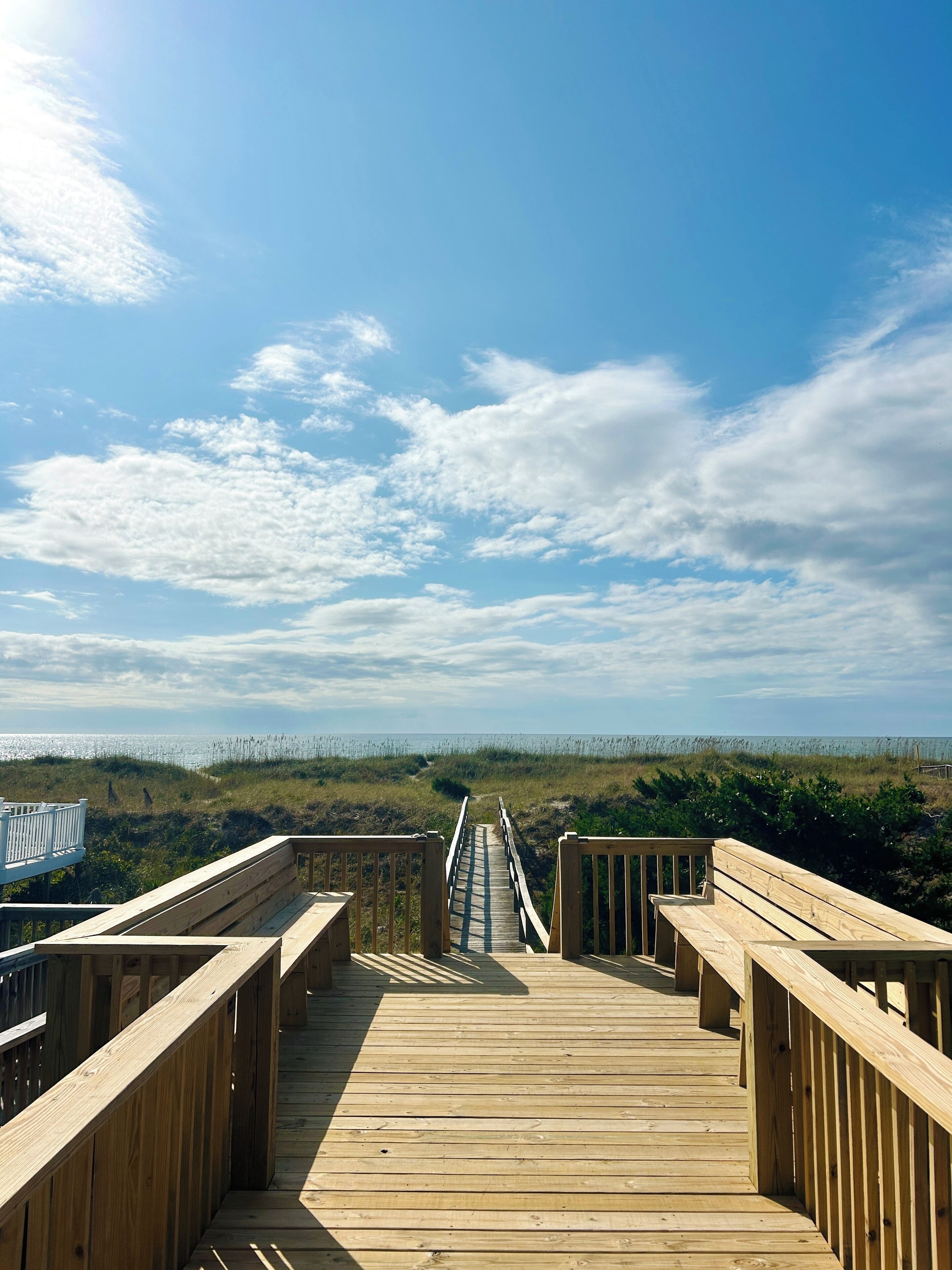 A wooden boardwalk leading to a beach with a clear sky.