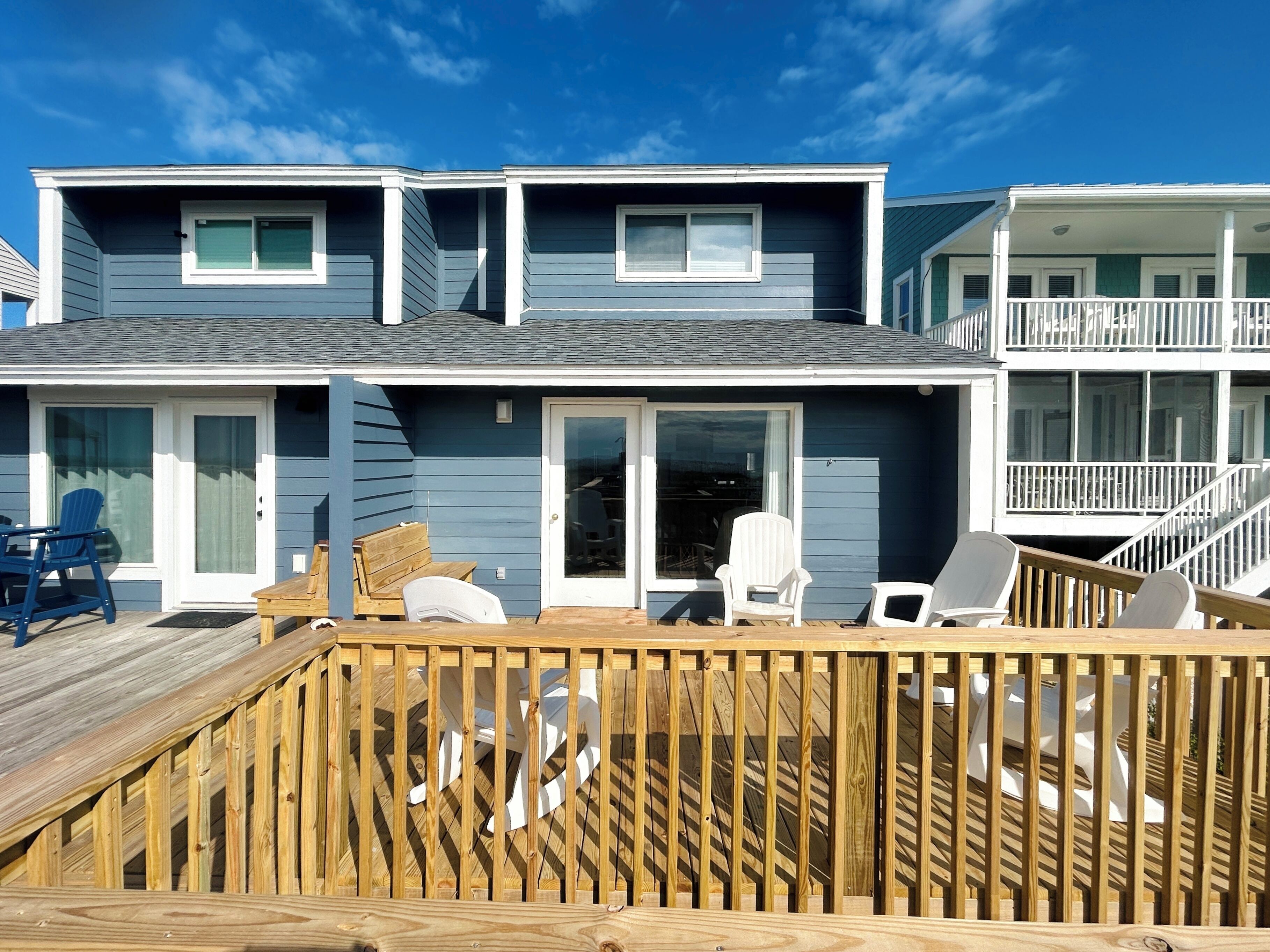 A two-story building with a deck, outdoor seating, and a covered area.