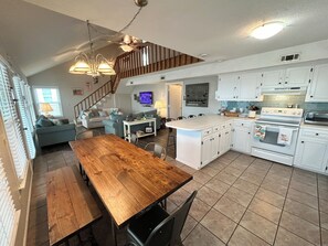 Een ruime keuken met witte kasten, een houten eettafel en een inbouwoven.