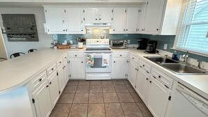 A kitchen with white cabinets, a stove, a microwave, and a sink. - 4BR, 2BA Holden Beach retreat located on the 2nd row (Holden Beach)