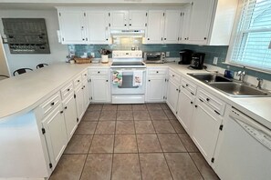 A kitchen with white cabinets, a stove, a microwave, and a sink. - 4BR, 2BA Holden Beach retreat located on the 2nd row (Holden Beach)