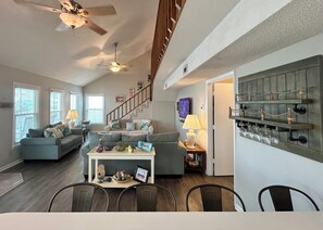 A spacious living area with a dining table, sofas, and a staircase leading to an upper level. - 4BR, 2BA Holden Beach retreat located on the 2nd row (Holden Beach)