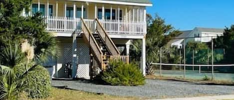 A two-story house with a porch, a staircase, and a fenced yard.
