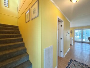 A staircase leading to a second floor, a door with a white frame, and a view of a balcony with a railing. - "Courtside" cozy 4 bedroom home, short walk to the Beach!! (Holden Beach)