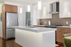 Una cocina moderna con una isla central, electrodomésticos de acero inoxidable e iluminación colgante.